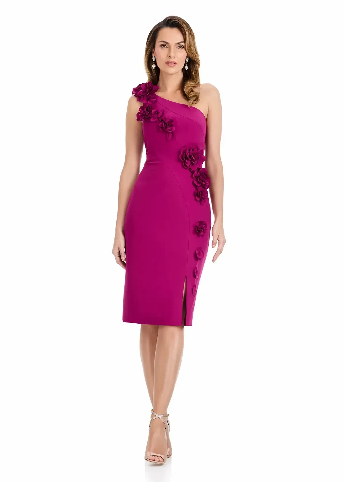 A woman wearing a one-shoulder fuchsia dress with floral embellishments and a side slit, standing against a white background.