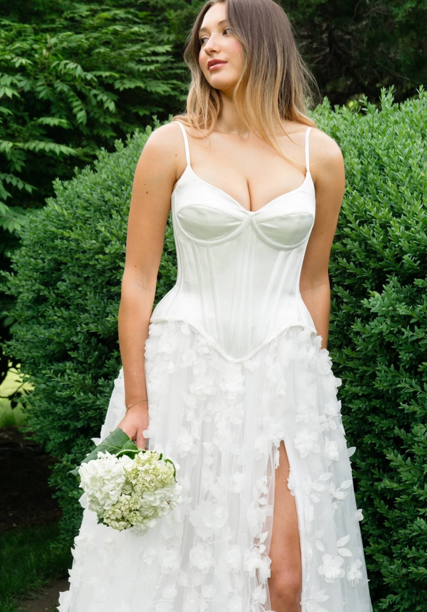 Model wearing Bridal dress leaning next to a car